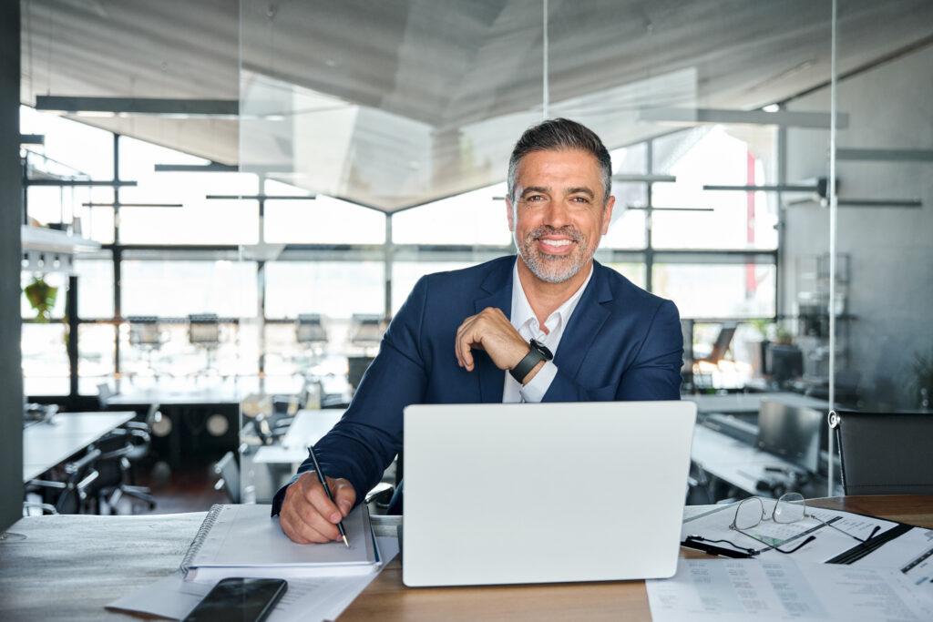 Happy business man working on laptop in modern office