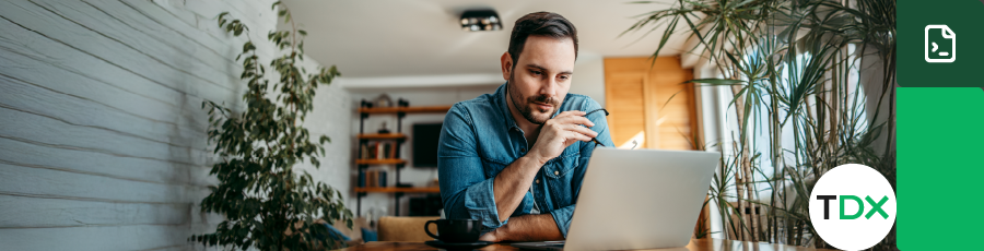 
Man with obscured face using laptop in a home office setting.