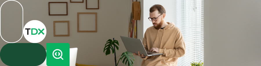 Person holding a laptop in a modern room with geometric shapes and ‘TDX’ logo