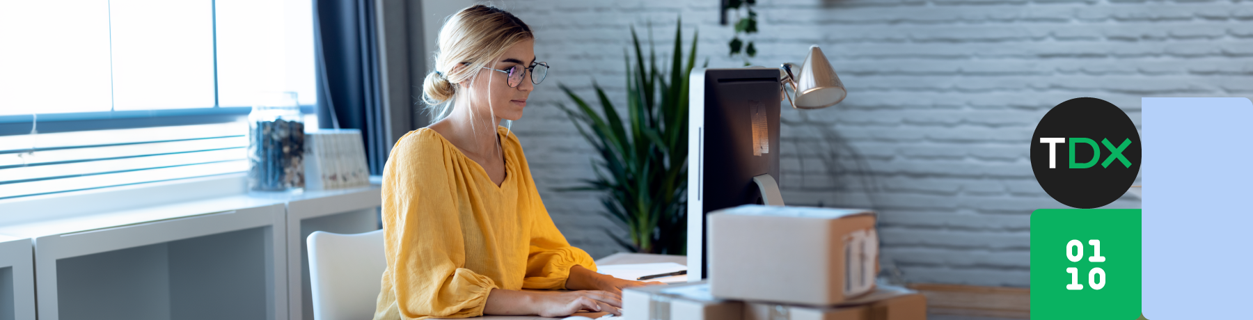 Woman in yellow top working at a desk with a computer and printer.

